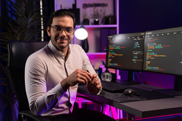 Profile's smart IT developer looking camera to pose with against on software development coding on...
