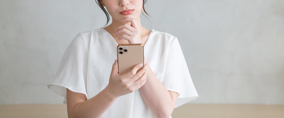 スマホを見て悩む女性
