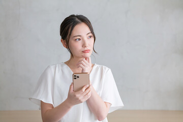 スマホを見て悩む女性