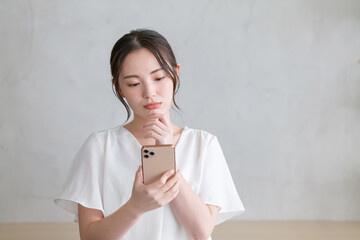 スマホを見て悩む女性