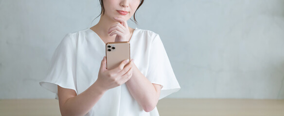 スマホを見て悩む女性