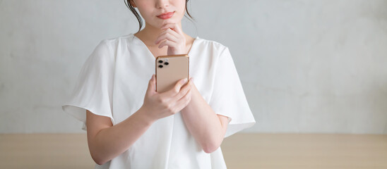 スマホを見て悩む女性