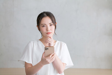 スマホを見て悩む女性