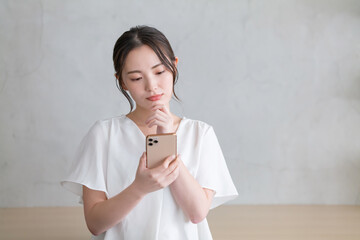 スマホを見て悩む女性