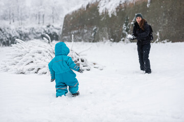 Mother and son playing snowballs in snowy landscape