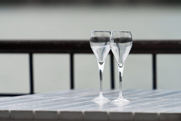Two transparent Trumpet-shaped glasses on a table in a summer cafe by the lake.