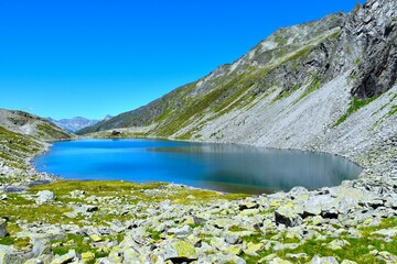 Beautiful Dösner lake with rocks and alpine meadows at the shore in High Tauern mountains, Carinthia, Austria
