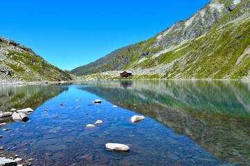 Mountain lodge at the shore of Dösnersee with a reflection in the water in High Tauern, Carinthia, Austria
