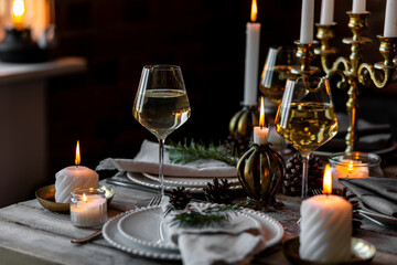 Rustic Scandinavian style zero waste eco-friendly dinner table decor for Christmas or new year family celebration. Wooden table, natural elements like pine cones, fir tree branches, candles