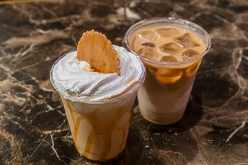 Iced coffee with whip cream on top, person holding a coffee cup