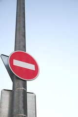Red no-entry traffic sign on metal pole, clear sky background. Do not enter round sign for cars, regulation on roads. Metaphor for stop doing something. Vertical backdrop with space for text