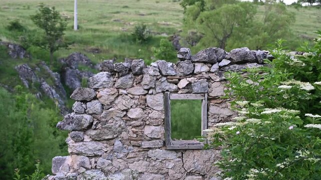 Ruins of house. A destroyed house in a village. Consequences of the war in the Balkans. A house destroyed by artillery. A burnt-out home in the forest. Remains of a wall and windows.