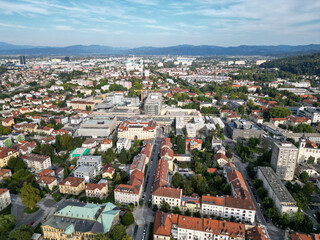 aerial view of ljubljana slovenia (european capital city in europe) castle on hill colorful roofs suburban neighborhood with mountains apartment buildings trees green nature hills river