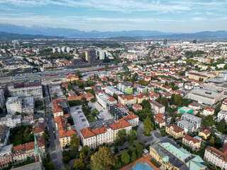 aerial view of ljubljana slovenia (european capital city in europe) castle on hill colorful roofs suburban neighborhood with mountains apartment buildings trees green nature hills river