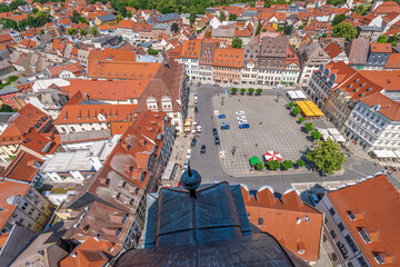 Aerial view of a picturesque European market square with historic buildings, red tiled roofs, trees, and cozy outdoor seating