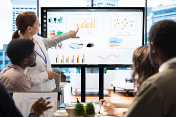 Staff members and shareholders gathering for a reports analysis in boardroom, studying infographics...