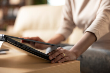 Close up of woman opening laptop lid on wooden table, beginning her remote work session. Female...