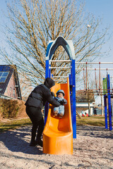 On this beautiful, sunny day, a joyful and carefree child happily slides down the slide at the...