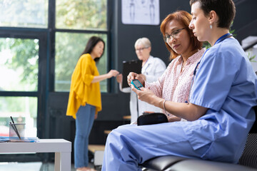 Hospital staff explaining glucometer use and blood sugar monitoring, doing a routine checkup for...