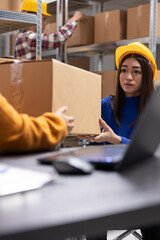 Asian staff member with disability manages packages in a startup warehouse. Working on order...