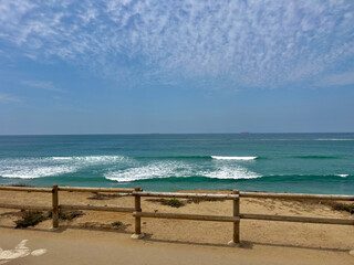 Wide view of a sunny beach coastline on a bright summer day in June in Huntington Beach, SoCal, Southern California, USA
