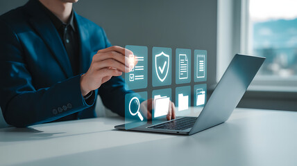 A person interacting with digital icons above a laptop on a white surface indoors