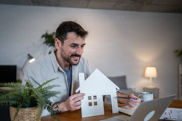 Architect showing house model during video call conference in home office
