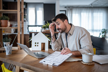 Architect feeling stressed while working at home on housing project