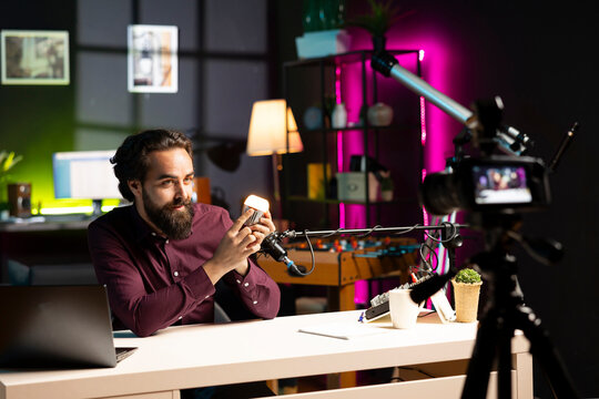 Smiling content creator filming smart light bulb review for online streaming platforms with professional mic. Cheerful media star films IoT home automation product with high quality equipment