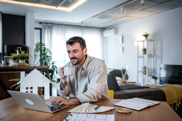 Architect drinking coffee and working on laptop at home