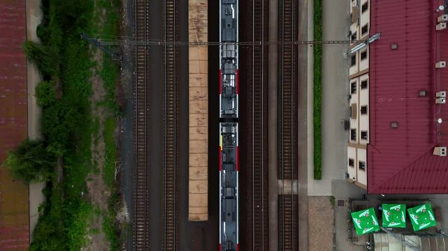 Aerial drone footage of a moving freight train traveling through diverse landscapes. The powerful locomotive pulls cargo cars along winding tracks, showcasing industrial transport and logistics effici