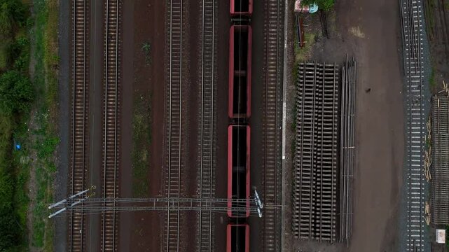 Aerial drone footage of a moving freight train traveling through diverse landscapes. The powerful locomotive pulls cargo cars along winding tracks, showcasing industrial transport and logistics effici