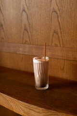 Refreshing iced chocolate drink in a glass on a rustic wooden surface. Perfect for cafe menus, beverage concepts, or food blogs.