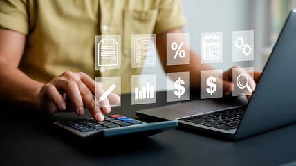Man using calculator and laptop with financial icons floating above the devices on desk