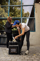 Female delivery person completing the meal order drop off by handing pizza boxes to a waiting...