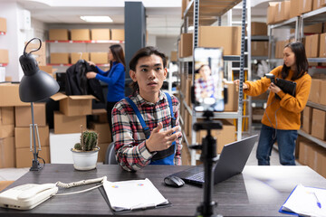 Small business owner uses a smartphone to film content inside fulfillment center, vlog highlighting...