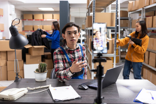Small business owner uses a smartphone to film content inside fulfillment center, vlog highlighting inventory, order processing and local delivery services for regional online promotion.