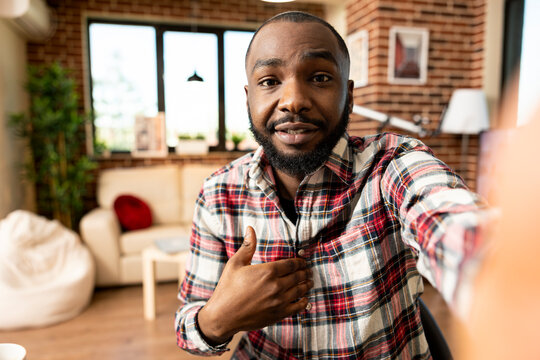 Young black male entrepreneur talks to viewers, vlogging on mobile phone, presenting business ideas. Self employed man having friendly online conversation using digital device at home.