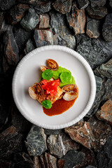 Halibut with Green Pea Puree, Vongole, and Black Garlic Emulsion on stones