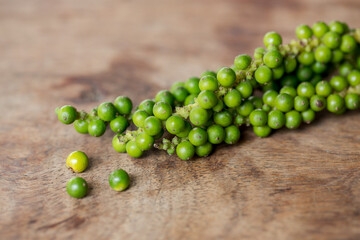 Unprocessed fresh green peppercorns on wooden table