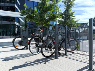 Bicycles parked at a modern bike rack surrounded by greenery and contemporary architecture