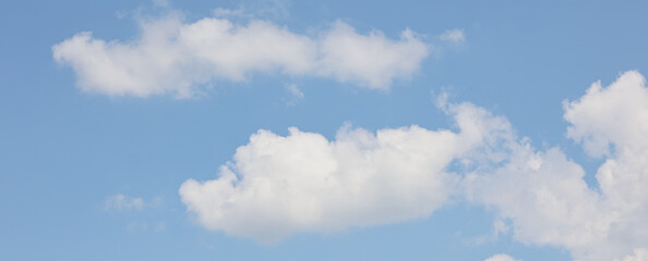 Beautiful white cumulus clouds gently float across a vast, clear blue sky, creating a tranquil and picturesque scene, perfect for backgrounds and nature-themed projects