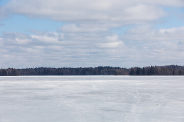 Snowmobile tire tracks crisscrossing the frozen surface of a lake, leading toward a distant...