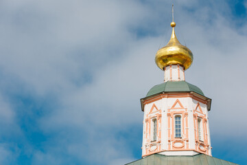 Golden cupola gleaming atop the church tower, featuring a vibrant green roof under a bright blue...