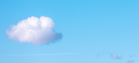 Solitary white cloud drifts serenely across a vibrant blue sky, creating a simple yet captivating...