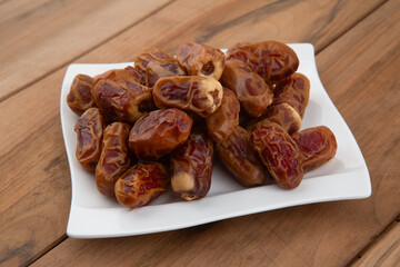 Date palm fruit (MedJool) on wooden plate