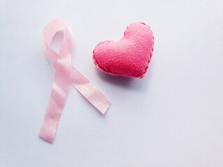heart and pink ribbon representing pink october, awareness against breast cancer in women on a blue...