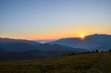 Breathtaking view of the sunrise illuminating hills, mountains and lush green valley, highlighting...