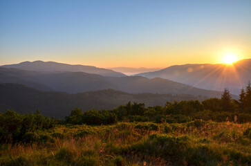 Breathtaking view of the sunrise illuminating hills, mountains and lush green valley, highlighting...