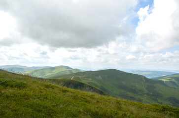 Vast green hills stretch under cloudy skies, offering a breathtaking view of nature's beauty....